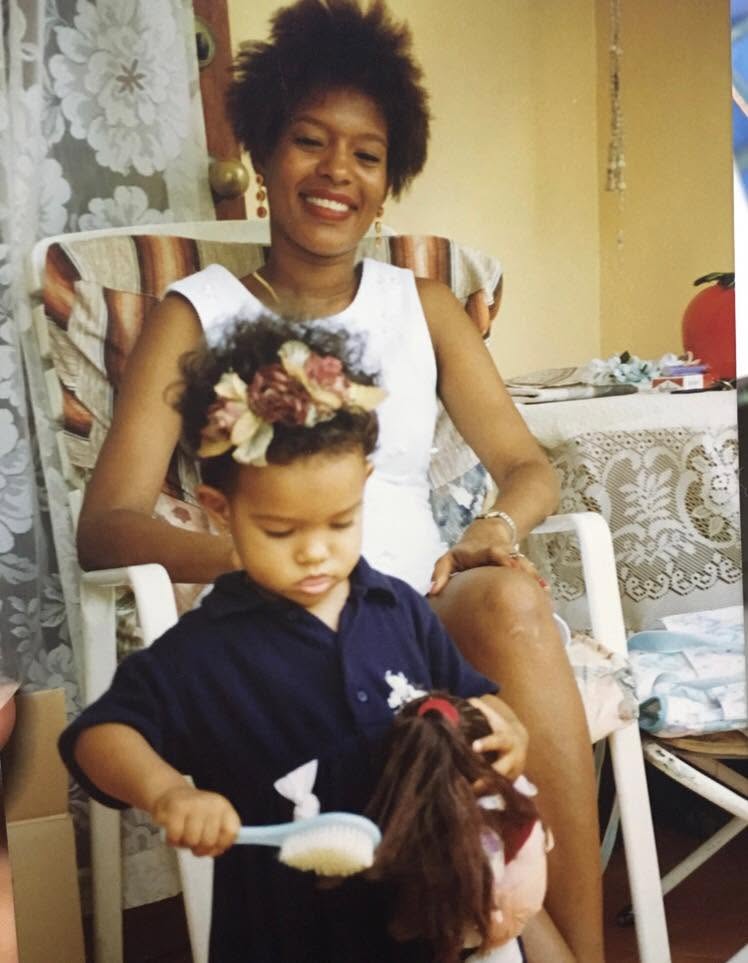 Joline smiling next to her little sister, who is brushing a doll's hair