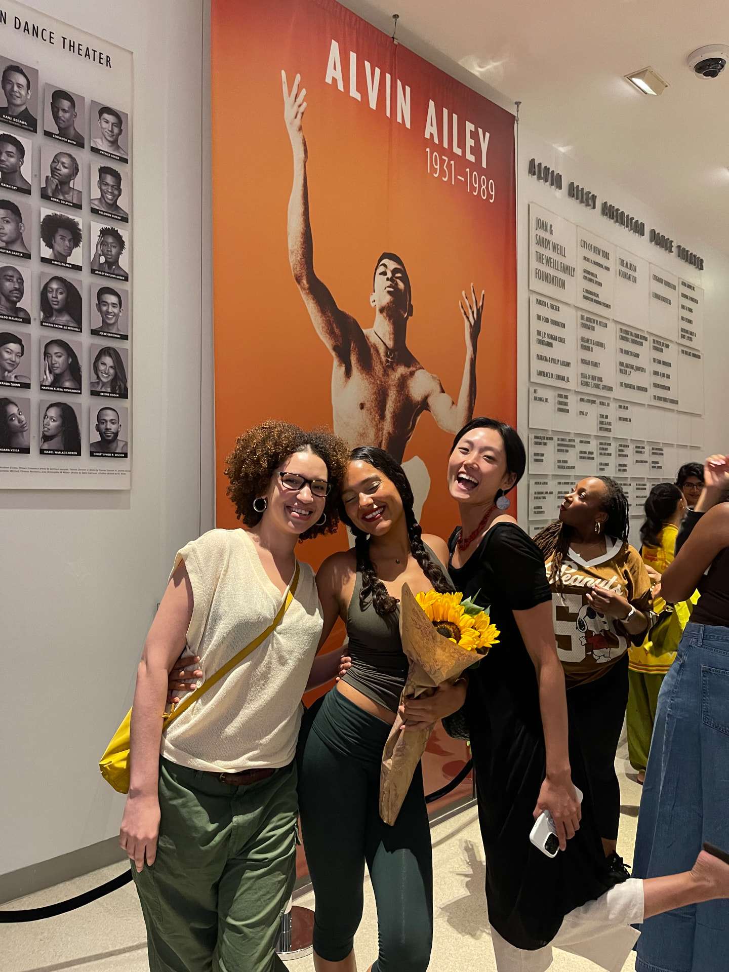 Joline with two friends holding sunflowers after a dance performance
